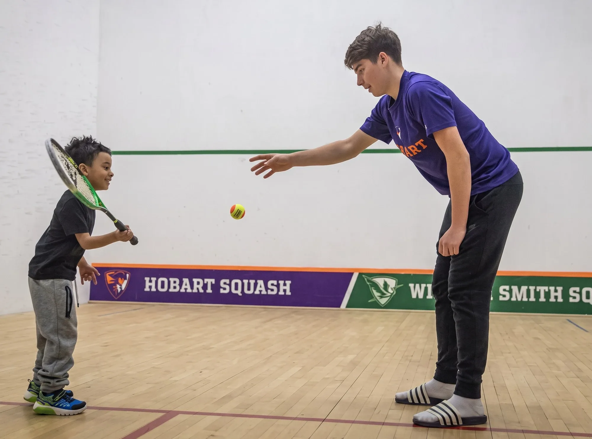 Coach feeding a ball to a junior player during a private lesson